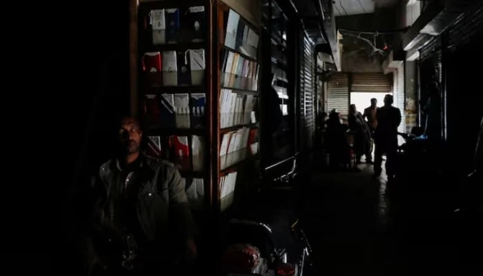 A man sits outside his shop during a country-wide power breakdown in Karachi, on January 23, 2023. — Reuters