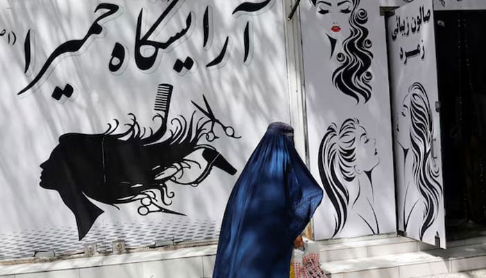 An Afghan woman walks past a beauty salon in Kabul, Afghanistan, July 6, 2023. — Reuters