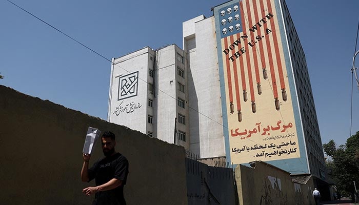 A man walks near an anti-U.S. mural on a building in Tehran, Iran, June 9, 2026. — Reuters