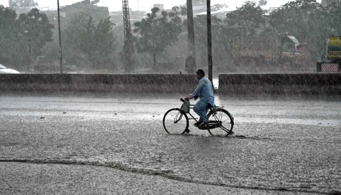 Cyclist pass through water accumulated at IJP Road during heavy rain in Islamabad, June 4, 2026. — APP