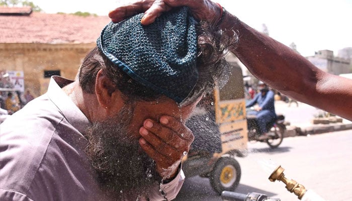 An Edhi Foundation volunteer sprays water on passersby to provide relief from the intense summer heat in Karachi. Online