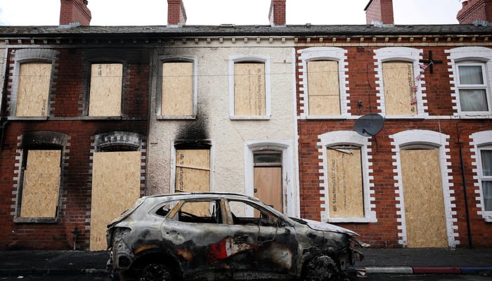 A burnt car stands in front of a boarded up house, in the aftermath of anti-immigrant protests following a knife attack on June 8, which left a man seriously injured and prompted police to declare a critical incident, at Lendrick street, east Belfast, Northern Ireland, June 10, 2026. — Reuters