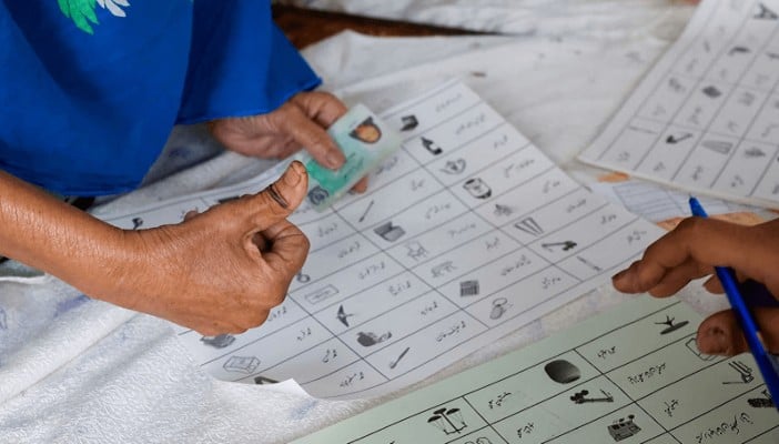 A voter with an ink mark on the thumb goes through paperwork to cast a vote during the general election in Karachi, February 8, 2024. — Reuters