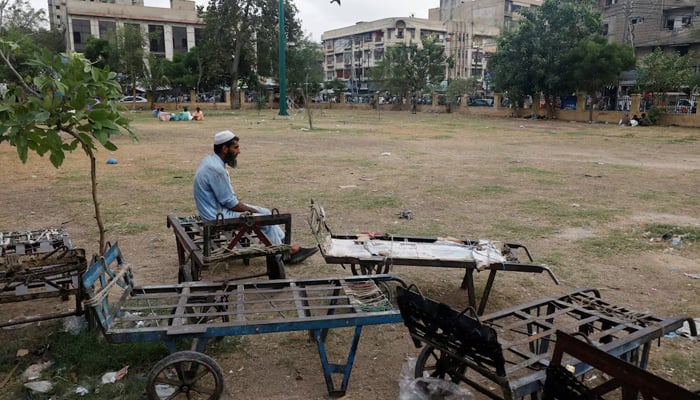 A labourer waits for work while sitting beside push trollies outside a market in Karachi, on June 8, 2023. — Reuters
