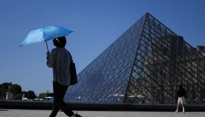 A person uses an umbrella to shelter from the sun outside the Louvre amid a heatwave in Paris, France, May 27, 2026. — Reuters