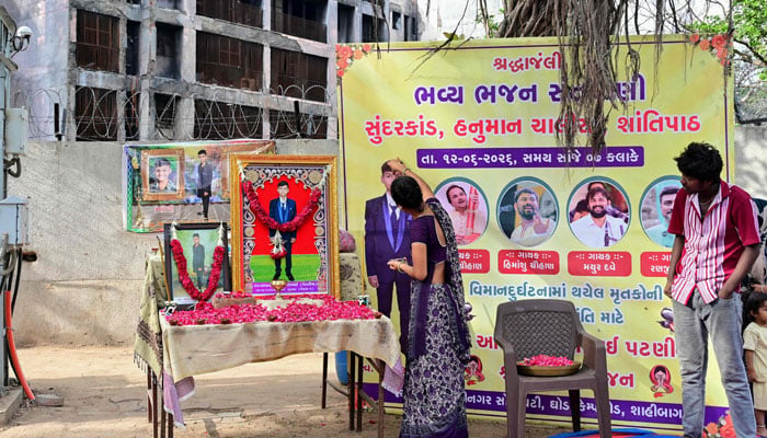 Family members of Air India plane crash victim Akash Patni pay tribute at remembrance portraits set up for him at the crash site on the first anniversary of the disaster in Ahmedabad on June 12, 2026. — AFP