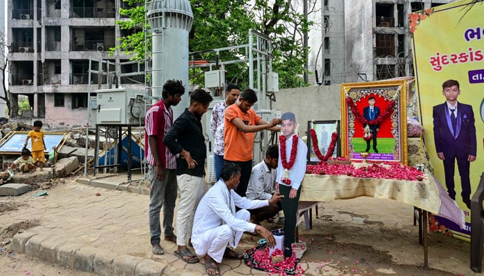 People set up portraits of Air India plane crash victim Akash Patni in tribute to him at the crash site on the first anniversary of the disaster in Ahmedabad on June 12, 2026.— AFP