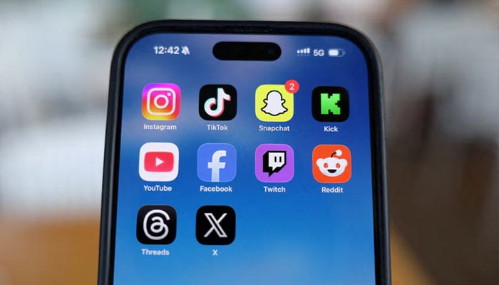 Instagram, TikTok, Snapchat, Kick, YouTube, Facebook, Twitch, Reddit, Threads and X applications are displayed on a mobile phone in this picture illustration taken on December 9, 2025. — Reuters