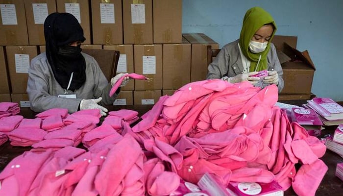 Women pack fabric sanitary pads in a tailor workshop. — AFP/File
