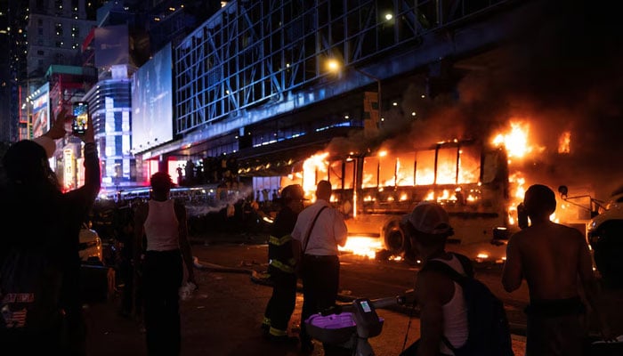 Revellers and fans celebrating the New York Knicks win over the San Antonio Spurs and World Cup festivities watch as a city shuttle bus catches fire outside the Port Authority Bus Terminal in New York, US, June 14, 2026.— Reuters