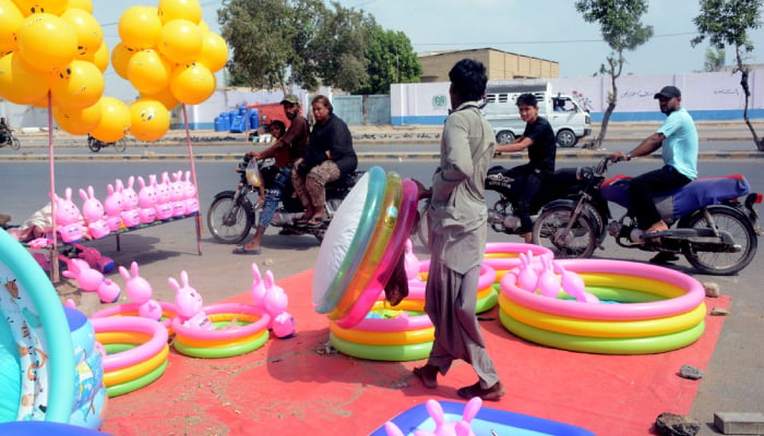 A vendor arranges colourful inflatable paddling pools, rubber rings and bunny toys at a roadside stall as customers show keen interest in the cooling products, June 13, 2026. — APP