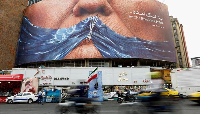 People drive past an anti-U.S. billboard depicting US President Donald Trump and the Strait of Hormuz, in Tehran, Iran, May 17, 2026. — Reuters