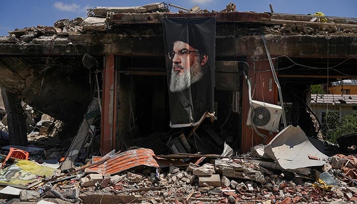 A banner with an image of late Hezbollah leader Hassan Nasrallah hangs from a destroyed building in Jibchit, Nabatieh district, Lebanon, June 16, 2026. — Reuters