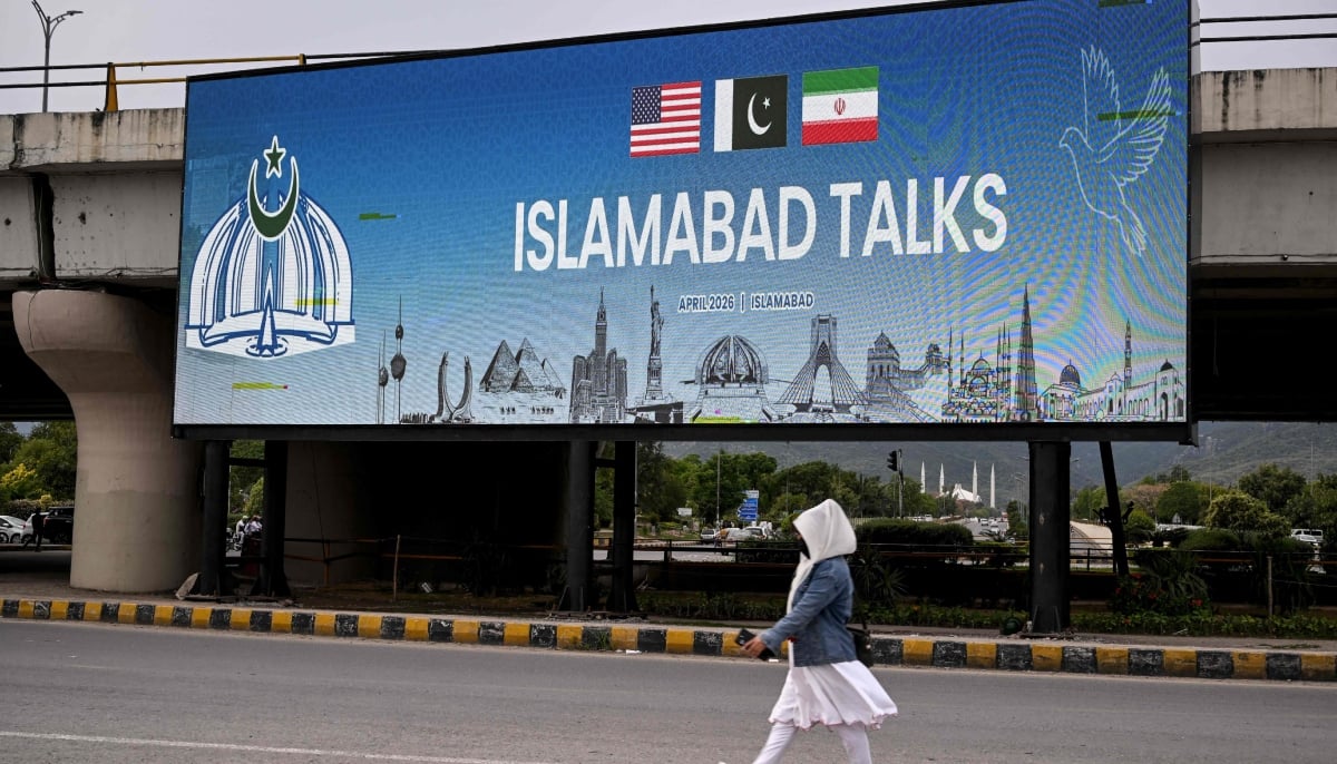 On April 8, 2026 Pakistan announced that the US and Iran had agreed to an immediate ceasefire and both parties to hold talks in Islamabad. In this picture, a woman walks past a digital screen displaying news of US-Iran peace talks along a road in Islamabad on April 10, 2026. — AFP