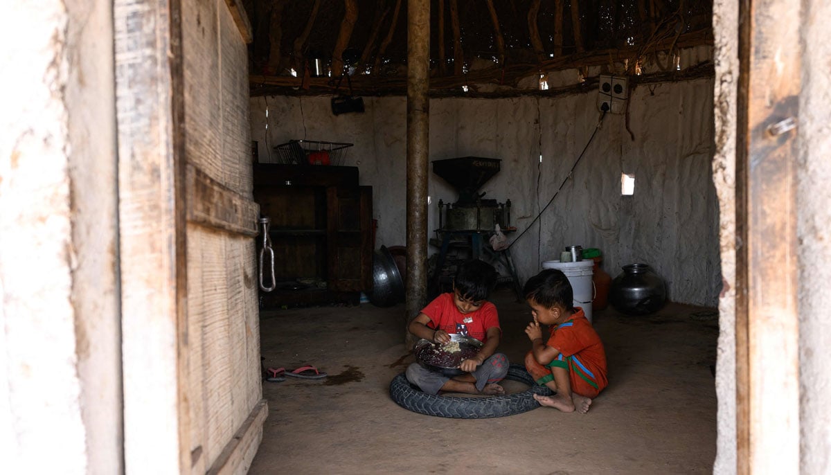 Herdsman Sawai Singh Bhatis sons Jeetu and Rahul have a meal inside a mud-kitchen in 42℃ temperatures, outside their house in Sanwata village on the outskirts of Rajasthan´s Jaisalmer city.— AFP