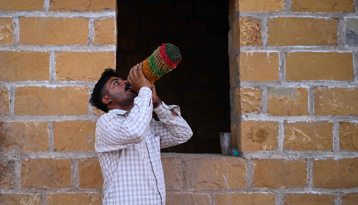 Image shows herdsman Sawai Singh Bhati drinking water from a bottle covered in handmade jute layer to keep it cool, after returing from work at his house in Sanwata village on the outskirts of Rajasthans Jaisalmer city.— AFP