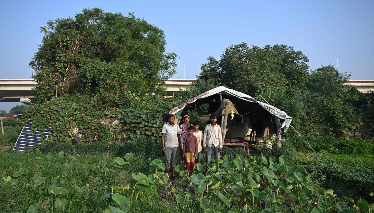 Farmer Bhole Shankar (L) posing for a family portrait in approximately 40℃ temperatures, outside their shanty on the Yamuna river floodplains in New Delhi.— AFP