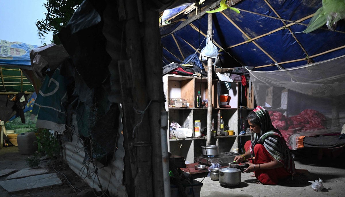 Image shows farmer Bhole Shankars wife, Debvati cooking dinner inside her shanty on the Yamuna river floodplains in New Delhi.— AFP