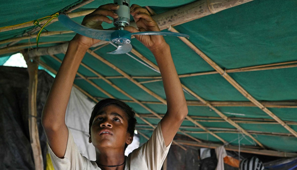 Farmer Bhole Shankar´s son, Tejpal fixing a portable electric fan in approximately 40℃ temperatures, inside his shanty on the Yamuna river floodplains in New Delhi. In the lush green banks of New Delhi´s Yamuna river floodplains. — AFP