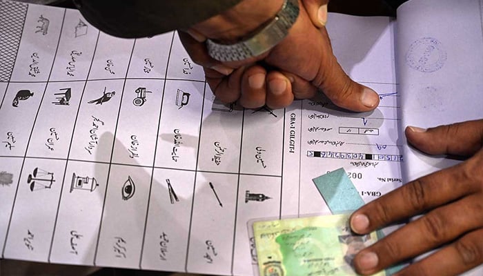 A voter stamps a ballot paper while holding his national identity card at a polling station during the Gilgit-Baltistan General Elections on June 7, 2026. — APP