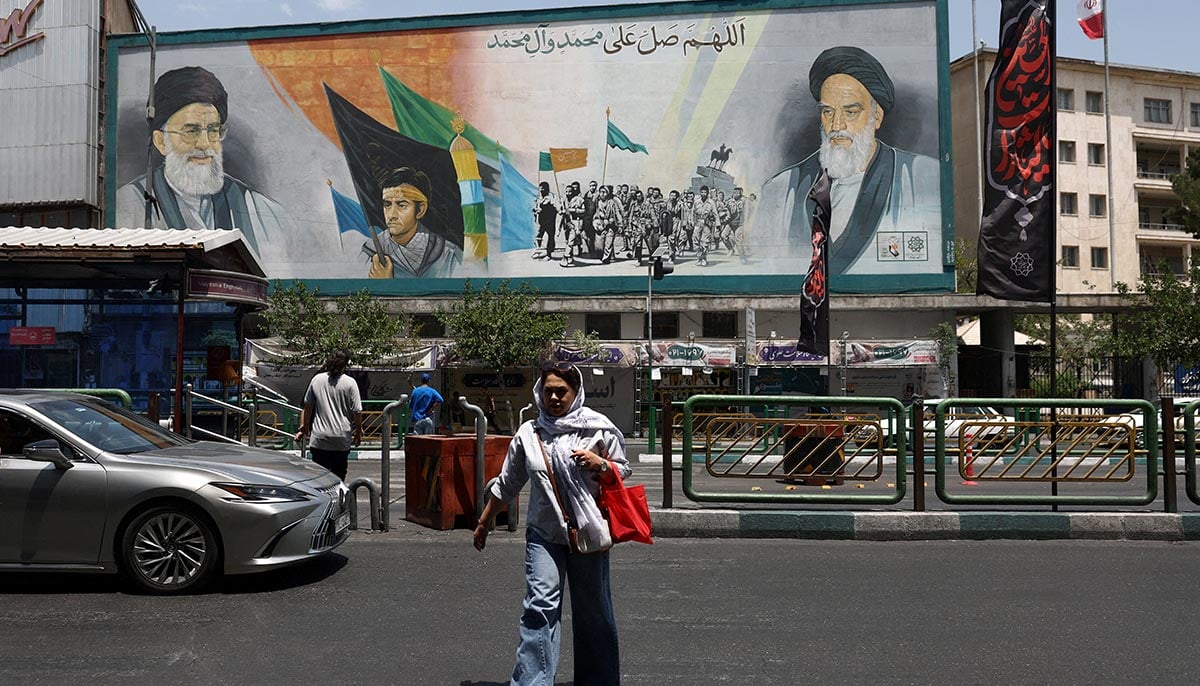 A woman walks near a mural depicting the late leader of the Islamic Revolution, Ayatollah Ruhollah Khomeini, and Irans late Supreme Leader Ayatollah Ali Khamenei, on a street in Tehran, Iran, June 18, 2026. — Reuters