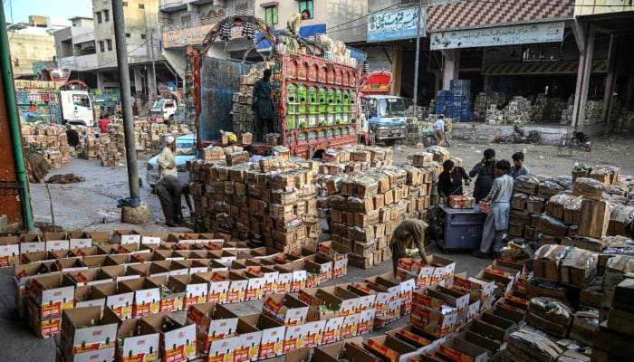 This photograph taken on June 5, 2026 shows workers loading boxes of mangoes onto a truck at a market in Karachi. — AFP