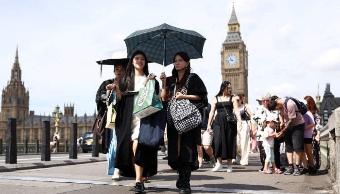 Women walk with a parasol across Westminster bridge during the hot summer weather in London, Britain, June 21, 2026. — Reuters