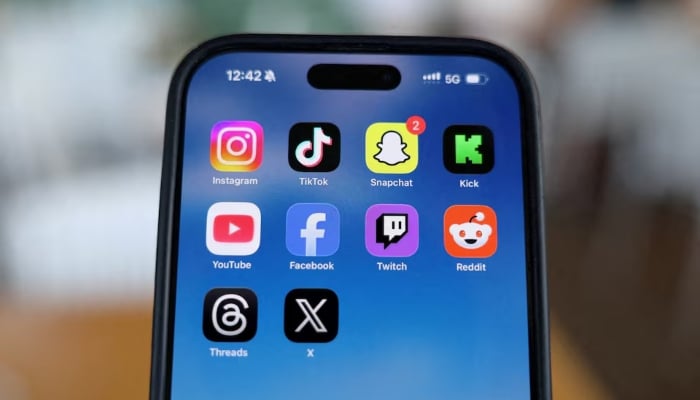 Instagram, TikTok, Snapchat, Kick, YouTube, Facebook, Twitch, Reddit, Threads and X applications are displayed on a mobile phone in this picture illustration taken on December 9, 2025. — Reuters