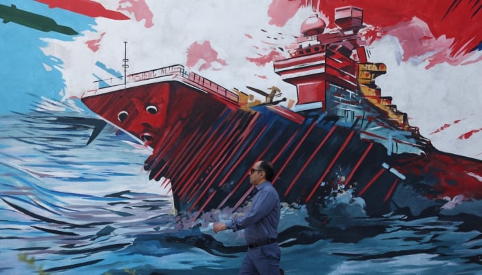 An Iranian man walks next to a mural on a street in Tehran, Iran, June 1, 2026. — Reuters