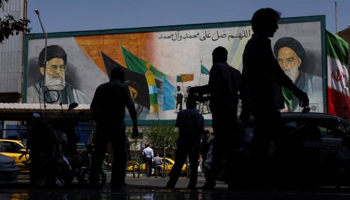 People walk past a mural depicting the late leader of the Islamic Revolution, Ayatollah Ruhollah Khomeini, and the late Irans Supreme Leader Ayatollah Ali Khamenei, in Tehran, Iran, May 12, 2026.— Reuters
