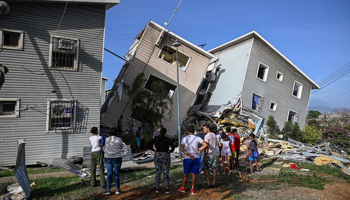 People stand before damaged homes following an earthquake in Catia La Mar, La Guaira state, some 30km north-west of Caracas, on June 25, 2026. — AFP