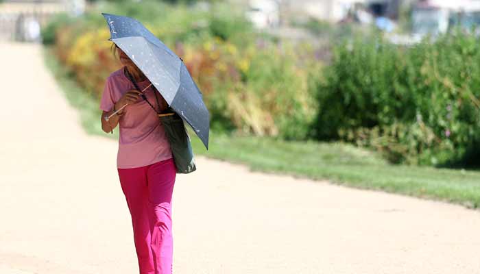A person uses an umbrella to shield from the sun whilst walking along the River Thames, as Britain experiences record temperatures disrupting schools and transport networks, at Richmond, in London, Britain, June 25, 2026.— Reuters