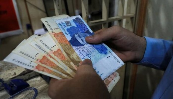 A man counts Pakistani rupee notes at a currency exchange shop in Peshawar, Pakistan September 12, 2023. — Reuters