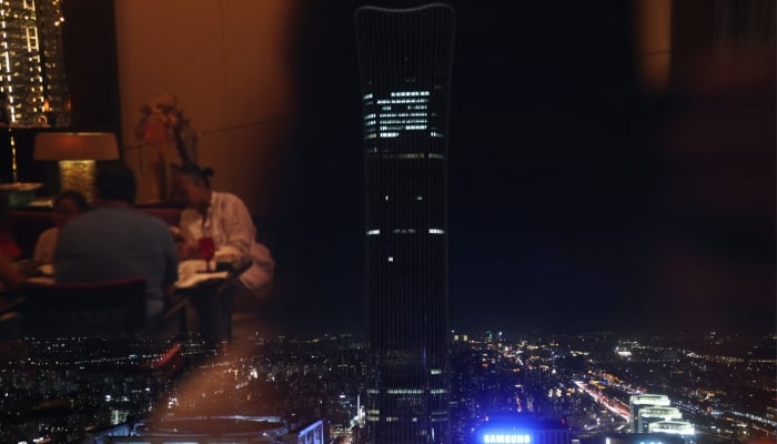 People sit reflected in a window overlooking the CITIC Tower, also known as China Zun, the tallest building in the Chinese capital, in Beijing, China, June 26, 2026. — Reuters
