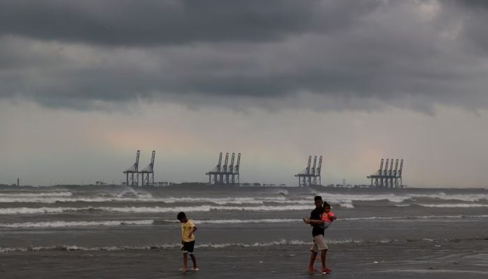 Children play, with the rainbow and rain clouds in the background, at Clifton Beach in Karachi, August 30, 2024. — Reuters