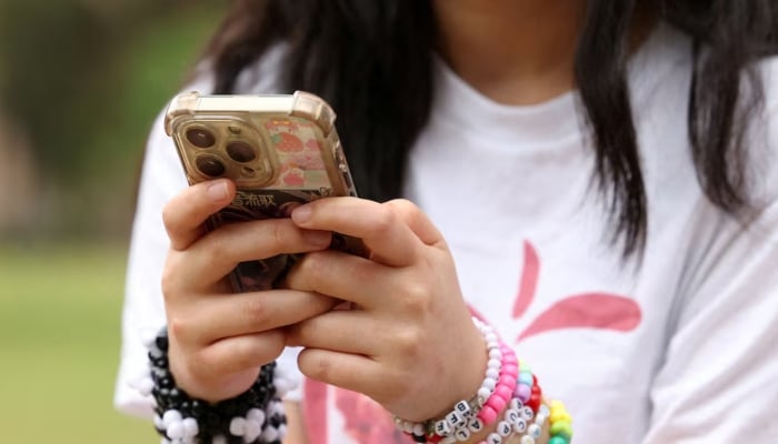 A girl poses holding her phone after an interview discussing Australias social media ban for users under 16. — Reuters/File
