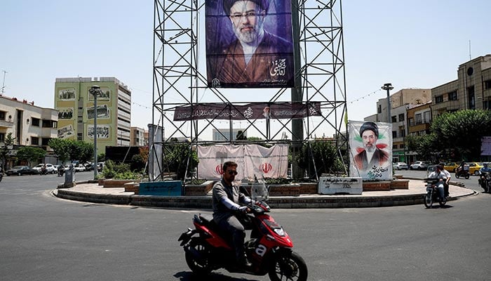 People ride past a banner with a picture of Irans Supreme Leader, Mojtaba Khamenei, in Tehran, Iran, June 28, 2026. — Reuters
