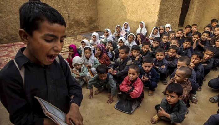 A boy recites from a book during a lesson at a school in a slum on the outskirts of Islamabad, October 11, 2013. — Reuters