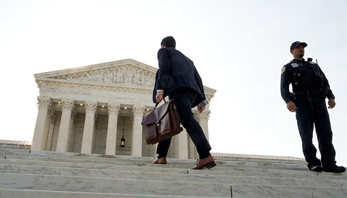 A man walks past a police officer standing in front of the Supreme Court building in Washington, DC, US, June 30, 2026. — Reuters