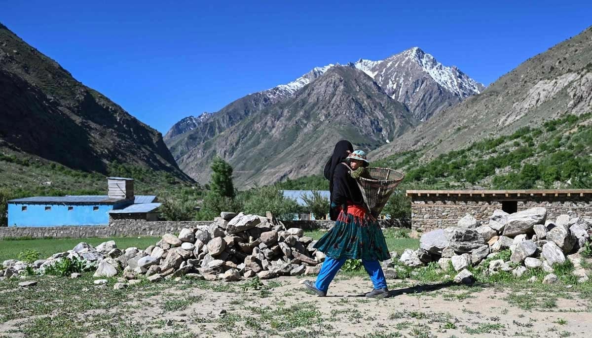 Afghan woman farmer Habiba carrying her granddaughter Saeeda on her way to work at a field in the Eshtiwi village of Afghanistans Parun district. — AFP