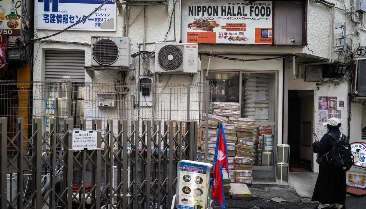 A woman stands near a South Asian store in the Okubo area, one stop north of Shinjuku metro, in Tokyo on June 12, 2026. — AFP