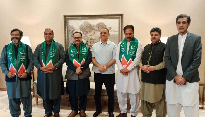 Federal minister Aleem Khan (centre) welcomes Tanveer Ilyas into the party by presenting him with the IPP party muffler during the meeting. — Geo News