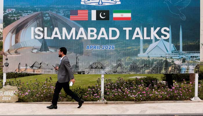 A man walks past a billboard near the media centre in Islamabad, April 11, 2026. — Reuters