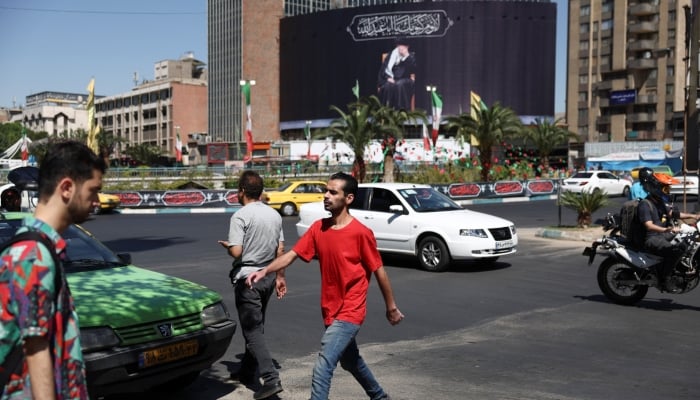 People walk past a billboard with a picture of the late Irans Supreme Leader Ayatollah Ali Khamenei, after US and Iranian officials said they had reached a deal to end their war and reopen the Strait of Hormuz, in Tehran, Iran, June 15, 2026. — Reuters