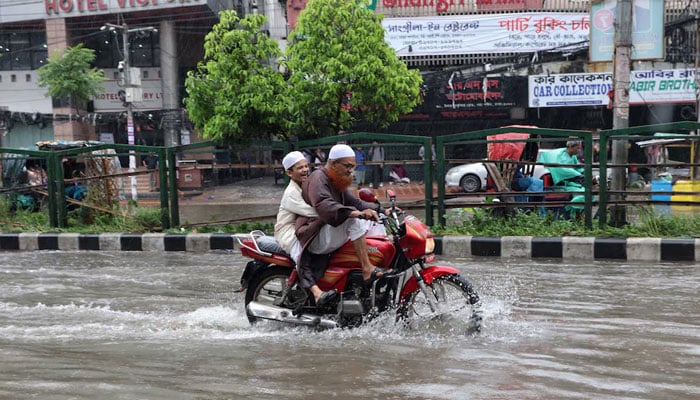 A child reacts while riding pillion on a motorcycle through a waterlogged street after heavy rainfall in Dhaka, Bangladesh, July 10, 2026. — Reuters