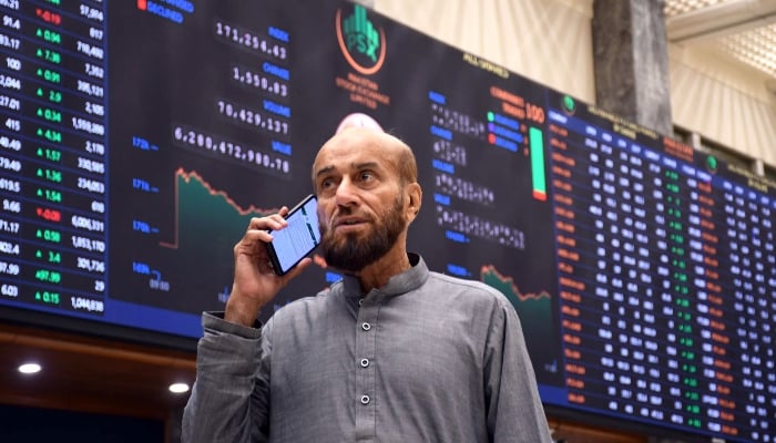 A broker talk on cell phone under the share prices screen at the PSX in Karachi, June 12, 2026. — ONLINE