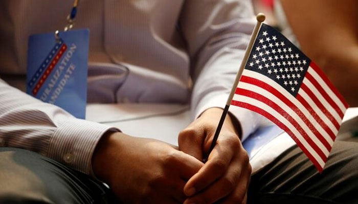 A new citizen holds a US flag at the US Citizenship and Immigration Services (USCIS) naturalization ceremony at the New York Public Library in Manhattan, New York, US, July 3, 2018. — Reuters
