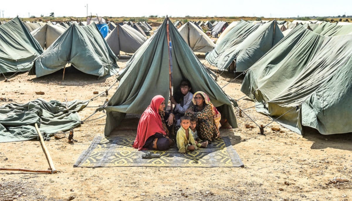 An internally displaced flood-affected family sits outside their tent at a makeshift tent camp in Sindhs Jamshoro district on September 28, 2022. — AFP