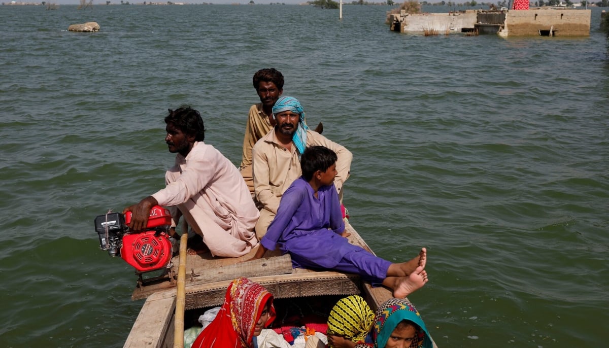 Residents ride on a wooden boat as they pass submerged houses amid flood water, following rains and floods during the monsoon season in Bajara village, at the banks of Manchar lake, in Sehwan on September 6, 2022. — Reuters
