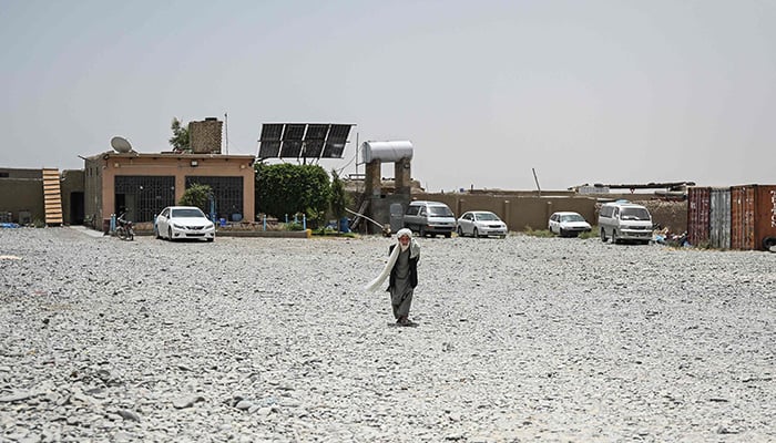 This photograph taken on June 18, 2026 shows an Afghan elderly man walking through a vacant container yard in the Spin Boldak district of Afghanistan´s Kandahar province. — AFP